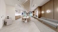 Located at 19 Centrepointe Drive in Ottawa, Ontario, this thoughtfully designed single-floor commercial space offers a refined and inviting atmosphere suited for work, collaboration, and casual gatherings. The interior showcases a cohesive modern aesthetic, anchored by warm wood-paneled walls that provide a sense of warmth and sophistication throughout.

The open-plan layout accommodates a variety of seating configurations. A long built-in banquette upholstered in a classic black-and-white stripe runs along the wood-paneled wall, paired with intimate pedestal tables and tucked-away nook seating — ideal for small meetings or quiet focus work. A central dining-style table with upholstered chairs serves as a versatile gathering point, while a separate lounge zone features rounded cream armchairs arranged around a dark side table.

A dedicated coffee and refreshment area lines one wall, complete with cabinetry and counter space, complemented by a bold typographic wall feature reading "But First, Coffee." A large-scale blue abstract artwork adds a vibrant focal point to the lounge area. A glass-partitioned enclosure provides an option for a semi-private workspace within the open floor plan.

The ceiling features a combination of slat detailing and recessed lighting, with pendant lights adding warmth overhead. Neutral large-format tile and plush carpet flooring define different zones, contributing to the space's polished, welcoming character.