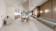 Located at 19 Centrepointe Drive in Ottawa, Ontario, this thoughtfully designed single-floor commercial space offers a refined and inviting atmosphere suited for work, collaboration, and casual gatherings. The interior showcases a cohesive modern aesthetic, anchored by warm wood-paneled walls that provide a sense of warmth and sophistication throughout.

The open-plan layout accommodates a variety of seating configurations. A long built-in banquette upholstered in a classic black-and-white stripe runs along the wood-paneled wall, paired with intimate pedestal tables and tucked-away nook seating — ideal for small meetings or quiet focus work. A central dining-style table with upholstered chairs serves as a versatile gathering point, while a separate lounge zone features rounded cream armchairs arranged around a dark side table.

A dedicated coffee and refreshment area lines one wall, complete with cabinetry and counter space, complemented by a bold typographic wall feature reading "But First, Coffee." A large-scale blue abstract artwork adds a vibrant focal point to the lounge area. A glass-partitioned enclosure provides an option for a semi-private workspace within the open floor plan.

The ceiling features a combination of slat detailing and recessed lighting, with pendant lights adding warmth overhead. Neutral large-format tile and plush carpet flooring define different zones, contributing to the space's polished, welcoming character.