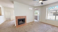 Located at 3830 E Lakewood Pkwy in Phoenix, AZ, this 2-bedroom, 2-bathroom single-floor residence offers a functional and comfortable layout. The living area is carpeted and centers around a tile-surround wood-burning fireplace, with a ceiling fan overhead and a transom window that draws in natural light. A sliding door leads to an outdoor balcony or patio, providing views of surrounding greenery. The kitchen features warm wood cabinetry, tile flooring, a full suite of black appliances including a refrigerator, range, and microwave, and a double-basin sink beneath a window. Both bedrooms are carpeted and include ceiling fans; the primary bedroom offers a walk-in closet and connects to the rest of the unit. One bathroom features a walk-in shower with grab bars and tile flooring, while the second bathroom includes a tub/shower combination, a vanity with wood cabinetry, and a large mirror. A dedicated laundry room houses a full-size washer and dryer with overhead shelving. The unit includes two closets throughout and maintains a clean, neutral palette with white walls and tile flooring in wet areas, creating a bright and cohesive living environment.