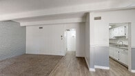 This well-appointed two-bedroom, one-bathroom residence offers a thoughtfully arranged single-floor layout with a variety of distinctive architectural details. The living room serves as the central gathering space, featuring exposed beamed ceilings with a textured finish, a ceiling fan, and a two-tone gray and white wall treatment. Wood-look flooring flows through the main living and kitchen areas, while carpet adds warmth to the bedrooms. A large sliding glass door in the living room fills the space with natural light.

The galley-style kitchen is efficiently designed with ample white cabinetry both above and below, granite-look countertops, a stainless steel sink, and white appliances including a refrigerator and range.

Both bedrooms showcase painted brick accent walls and exposed beam ceilings, lending a distinctive character to each room. Each bedroom is carpeted and includes a closet — one with sliding doors and one with a hinged door — providing practical storage. The primary bedroom is generously sized to comfortably accommodate standard furnishings.

The bathroom features a vanity with a granite-look countertop and white cabinetry, wood-look tile flooring, and a separate tub-shower combination with a window for natural light. The overall aesthetic is clean, neutral, and move-in ready.