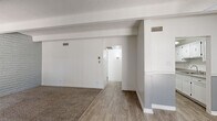 This well-appointed two-bedroom, one-bathroom residence offers a thoughtfully arranged single-floor layout with a variety of distinctive architectural details. The living room serves as the central gathering space, featuring exposed beamed ceilings with a textured finish, a ceiling fan, and a two-tone gray and white wall treatment. Wood-look flooring flows through the main living and kitchen areas, while carpet adds warmth to the bedrooms. A large sliding glass door in the living room fills the space with natural light.

The galley-style kitchen is efficiently designed with ample white cabinetry both above and below, granite-look countertops, a stainless steel sink, and white appliances including a refrigerator and range.

Both bedrooms showcase painted brick accent walls and exposed beam ceilings, lending a distinctive character to each room. Each bedroom is carpeted and includes a closet — one with sliding doors and one with a hinged door — providing practical storage. The primary bedroom is generously sized to comfortably accommodate standard furnishings.

The bathroom features a vanity with a granite-look countertop and white cabinetry, wood-look tile flooring, and a separate tub-shower combination with a window for natural light. The overall aesthetic is clean, neutral, and move-in ready.
