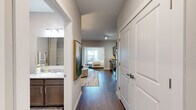 This single-story residence in Little Rock, Arkansas, presents a thoughtfully designed layout that balances comfort and modern style. Rich hardwood-style flooring flows continuously throughout the unit, creating visual cohesion from the entry corridor to the living and sleeping areas. Neutral gray-toned walls provide a clean, versatile backdrop that complements the overall contemporary aesthetic.

The kitchen is well-appointed with stainless steel appliances, including a range, over-the-range microwave, and refrigerator, paired with granite-style countertops and taupe shaker-style cabinetry offering ample storage. The kitchen opens directly to the living area, which is generously proportioned and filled with natural light, creating an inviting space for everyday living.

The bedroom is a serene retreat, featuring a ceiling fan, natural light from well-positioned windows, and direct sightlines to both the kitchen and the hallway. A walk-in closet provides practical storage. The bathroom features a vanity with granite-style countertops, dark cabinetry, and a clean, neutral finish, while a separate water closet adds privacy and functionality. The entry hallway connects all areas efficiently, reinforcing the unit's smart, open flow.