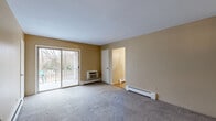Located at 205 Charlotte Court in Central Valley, NY, this one-bedroom, one-bathroom residence offers a practical and well-organized single-floor layout. The entrance leads into a hallway connecting the key living areas. The carpeted living room is a comfortable, open space featuring sliding glass doors that open onto a private patio, allowing natural light to flow in and providing outdoor views of surrounding trees. Baseboard heating is present throughout the unit. The dining room is finished with light hardwood flooring, a classic brass chandelier, and a large window that brings in additional natural light — it connects directly to the kitchen. The kitchen is equipped with warm oak cabinetry, granite-style countertops, a stainless steel sink, and white appliances including a refrigerator, range, and dishwasher. The spacious bedroom features plush carpeting, a large window overlooking the wooded surroundings, and direct access to a generously sized walk-in closet with built-in shelving. The full bathroom includes white tile walls and flooring, a single vanity with mirror, and a tub-shower combination. A staircase and dedicated closet complete this thoughtfully arranged home.