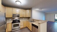 This single-floor unit at 4338 Snelling Ave in Minneapolis, MN offers a well-organized layout designed for practical everyday living. The kitchen serves as a central feature, equipped with stainless steel appliances including a refrigerator, electric range, built-in microwave, and dishwasher. Light maple cabinetry extends to the ceiling, providing generous storage, while a peninsula counter creates a natural division between the kitchen and the adjacent living and dining areas. Wood-look hard flooring runs throughout the main living spaces, lending a cohesive and easy-to-maintain aesthetic.

The living and dining areas are open and versatile, with neutral wall tones and wood baseboard trim throughout. A window in the bedroom area allows natural light and views of the surrounding greenery. Bedrooms feature plush carpeting and include walk-in and sliding-door closet options, offering substantial storage. The hallway connects the sleeping areas efficiently to the bathroom, which is finished with large-format stone-look tile surrounding the full soaking tub and shower combination, complemented by warm wood vanity cabinetry. Textured ceilings are consistent throughout the unit.