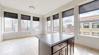 Located at 730 Hennepin Ave in the heart of Minneapolis, this two-bedroom, two-bathroom residence offers a thoughtfully designed single-floor layout. Distinctive terrazzo flooring flows consistently throughout the entire space, lending a polished, cohesive aesthetic to every room.

The kitchen is a standout feature, showcasing rich dark-wood cabinetry reaching toward the ceiling, gray stone-toned countertops, black appliances including a range, dishwasher, refrigerator, and microwave, along with a central island that provides additional prep and storage space. Large windows surrounding the kitchen area frame impressive panoramic views of the Minneapolis downtown skyline, filling the space with natural light.

Both bedrooms are well-proportioned and include built-in closets with wire shelving systems, offering practical storage solutions. Light wood trim and doors provide a clean, modern contrast throughout. The hallway connects the rooms efficiently, featuring a ceiling light fixture and a thermostat for climate control.

Each of the two bathrooms is finished with rich dark-wood vanities, white countertops, full bathtub and shower combinations, and coordinating terrazzo flooring, maintaining the consistent design language of the residence. The overall ambiance is clean, urban, and functional, well-suited for city living in a prime Minneapolis location.