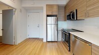 Located in Los Angeles, CA 90006, this modern single-floor unit showcases a clean, contemporary design throughout. Light wood-tone flooring flows seamlessly across all rooms, creating a cohesive and airy atmosphere that enhances the sense of openness.

The kitchen is a standout feature, equipped with full stainless steel appliances including a refrigerator, range, built-in microwave, and dishwasher. Textured wood-grain cabinetry extends from floor to ceiling, offering generous storage, while white countertops provide a crisp contrast. Track lighting overhead ensures excellent task illumination.

The open-concept living area benefits from floor-to-ceiling windows that invite an abundance of natural light and offer views of the surrounding Los Angeles cityscape. The bright white walls amplify the natural light, creating a welcoming and versatile living space.

The bedroom continues the light and minimal aesthetic, featuring large windows that frame outdoor views and a closet with sliding doors for efficient storage.

The bathroom is finished with a wood-grain vanity topped with a white countertop, a large mirror, and light-toned flooring that ties the space together with the rest of the unit. The overall design is clean, functional, and well-suited for modern urban living in Los Angeles.