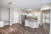 Located in San Diego's University City neighborhood, this one-bedroom, one-bathroom residence offers a well-designed layout across a single floor. The open-concept kitchen and living area serves as the heart of the home, where wood-style flooring flows seamlessly underfoot. The kitchen is outfitted with stainless steel appliances — including a refrigerator, range, and microwave — complemented by granite countertops, a granite-topped breakfast bar, and crisp white cabinetry that provides ample storage. Track lighting adds a modern touch overhead. The living area transitions to plush carpet and is anchored by a sliding glass door fitted with vertical blinds, opening to a private outdoor space and allowing natural light to fill the room. The generously sized bedroom features soft carpet, a ceiling fan with light, a window with exterior views, and direct access to a spacious walk-in closet equipped with wire shelving and hanging rods. The bathroom is finished with wood-style flooring, a granite-topped vanity with white cabinetry, and a full tub-shower combination. A hallway connects the key areas of the home, completing this functional and comfortable San Diego residence.