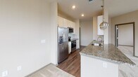 Located at 22415 Market St. in Cornelius, NC, this single-floor residence offers a thoughtfully designed layout with modern finishes throughout. The open-concept kitchen is a standout feature, showcasing granite countertops on a generous peninsula with an undermount sink, white shaker-style cabinetry, a classic subway tile backsplash, and a full suite of stainless steel appliances including a side-by-side refrigerator, electric range, and microwave. Stylish pendant lighting adds a contemporary touch above the kitchen peninsula, which flows seamlessly into the adjacent carpeted living area. The bedrooms are well-proportioned, each featuring plush carpet flooring, ceiling fans, and bright windows that invite natural light and offer views of the surrounding neighborhood. Multiple bedrooms include walk-in closets outfitted with wire shelving systems for organized storage. The bathrooms are finished with granite countertops and white cabinetry; the primary bathroom features a dual-sink vanity with a large mirror and access directly to the walk-in closet. A secondary bathroom offers a single-sink vanity with matching granite finishes and wood-look flooring. Neutral warm tones and clean lines create a cohesive, welcoming ambiance throughout the entire space.
