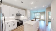 This well-appointed one-bedroom, one-bathroom unit at 640 Lakeside Dr in Canton, Georgia offers a thoughtfully designed single-floor layout with modern finishes throughout. The open-concept kitchen and living area serves as the heart of the home, anchored by a large central island with a white quartz countertop, undermount sink, and matte black fixtures. The kitchen features floor-to-ceiling white shaker cabinets, a marble-effect tile backsplash, stainless steel appliances including a refrigerator with ice maker, range, and built-in microwave, all complemented by warm wood-look flooring that flows seamlessly through the space. The living area receives generous natural light and provides access to an outdoor balcony through a glass-panel door, offering pleasant views of surrounding greenery. The bedroom is a comfortable retreat with a ceiling fan, natural light from a large window, and direct access to a walk-in closet outfitted with wire shelving. The full bathroom is finished in a clean, neutral palette with a tub-shower combo, white vanity with quartz countertop, and coordinating matte black hardware. Shaker-style interior doors and consistent light hardwood flooring unify the home's cohesive, contemporary aesthetic.