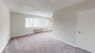 Located at 57 Galveston St SW in Washington, DC, this one-bedroom, one-bathroom unit offers a well-organized single-floor layout designed for efficient, comfortable living. The open living and dining area is one of the most prominent spaces in the unit, featuring plush wall-to-wall carpeting, neutral beige walls, a textured ceiling, and a large picture window that invites generous natural light while providing views of the surrounding neighborhood. A wall-mounted radiator and built-in HVAC unit provide climate control throughout the seasons. The kitchen is thoughtfully positioned adjacent to the living and dining space, equipped with white cabinetry, a range, and ample counter space. The bedroom is a well-proportioned retreat, also finished with soft carpeting and complemented by a ceiling fan with light fixture, a radiator, and a window with blinds that allows natural light while maintaining privacy. Three closets distributed throughout the unit offer notable storage capacity. The bathroom is clean and functional, featuring a full tub-shower combination with white tile surround, a vanity with under-cabinet storage, and a window for ventilation. A hallway connects the rooms cohesively, completing this practical and well-laid-out Washington, DC residence.