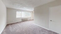 Located at 57 Galveston St SW in Washington, DC, this one-bedroom, one-bathroom unit offers a well-organized single-floor layout designed for efficient, comfortable living. The open living and dining area is one of the most prominent spaces in the unit, featuring plush wall-to-wall carpeting, neutral beige walls, a textured ceiling, and a large picture window that invites generous natural light while providing views of the surrounding neighborhood. A wall-mounted radiator and built-in HVAC unit provide climate control throughout the seasons. The kitchen is thoughtfully positioned adjacent to the living and dining space, equipped with white cabinetry, a range, and ample counter space. The bedroom is a well-proportioned retreat, also finished with soft carpeting and complemented by a ceiling fan with light fixture, a radiator, and a window with blinds that allows natural light while maintaining privacy. Three closets distributed throughout the unit offer notable storage capacity. The bathroom is clean and functional, featuring a full tub-shower combination with white tile surround, a vanity with under-cabinet storage, and a window for ventilation. A hallway connects the rooms cohesively, completing this practical and well-laid-out Washington, DC residence.
