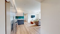 Located at 2137 Dwight Way in Berkeley, CA, this six-bedroom, two-bathroom unit offers a thoughtfully designed layout across a single floor. Light hardwood flooring flows throughout, complementing the clean, contemporary aesthetic. The open kitchen is a standout feature, boasting two-tone cabinetry in slate blue and light gray, quartz countertops, a vibrant teal backsplash, and stainless steel appliances including a range, dishwasher, and microwave. The adjoining living room is bright and welcoming, with multiple windows framing city and hillside views, recessed lighting, and an in-unit stacked washer and dryer conveniently tucked into the space. Each of the six bedrooms is compact yet functional, featuring light-filled windows with city views, light wood platform beds with built-in storage drawers, and dedicated workspace areas. The two bathrooms are finished with marble-style quartz vanity tops, slate blue cabinetry with black hardware, tub-shower combinations with white subway tile surrounds, and large framed mirrors. A connecting hallway with light hardwood flooring and crisp white walls ties all rooms together. This unit offers modern, efficient living in the heart of Berkeley.