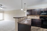 Located at 344 Murray Farm Dr in Fairview, TX, this single-story, one-bedroom, one-bathroom home offers a thoughtfully designed layout that maximizes every square foot. The open-concept kitchen flows seamlessly into the living area, creating a connected and functional living space. The kitchen is a standout feature, showcasing rich dark espresso cabinetry, granite-style countertops, a tile backsplash, and wood-look flooring. A peninsula with pendant lighting and an undermount sink adds both style and utility, while black appliances — including a range, built-in microwave, refrigerator, and dishwasher — complete the space. A dedicated pantry provides additional storage convenience. The bedroom is a comfortable retreat with plush carpeting, crown molding, a ceiling fan, and a window that invites natural light. Two closets, including a walk-in with multi-tier wire shelving, offer ample storage. The bathroom features dark wood cabinetry, a granite-style vanity top, a tub-shower combination with tile surround, and wood-look flooring. Additional highlights include a hallway, laundry area, and utility room, all finished with crown molding and neutral tones throughout, lending the home a clean and cohesive aesthetic.