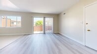 Located in Los Angeles' 90008 neighborhood, Unit 14 at 3910 Coco Ave is a well-appointed 2-bedroom, 1-bathroom unit spread across a single floor. The living room is a standout feature, bathed in natural light through a large sliding glass door that opens to a private outdoor balcony area, offering pleasant neighborhood views. Light gray wood-style flooring flows throughout the living spaces and bedrooms, contributing to a clean, cohesive aesthetic. The kitchen features a galley-style layout with white shaker cabinetry, dark countertops, stainless steel appliances including a refrigerator and dishwasher, and light tile flooring, offering an efficient and stylish space for meal preparation. Both bedrooms are well-sized, each equipped with ceiling fans, windows with blinds for natural light and privacy, and sliding-door closets providing ample storage. The primary bedroom offers a comfortable footprint suited for a full bedroom suite. The bathroom is finished with marble-style tile surrounding the shower/tub combo, white vanity cabinetry, and a dark countertop, echoing the design language found throughout the unit. A connecting hallway ties all rooms together in a functional and organized floor plan.
