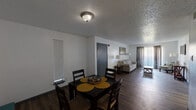 This single-story, 2-bedroom, 1-bathroom home in Port Arthur, Texas offers a practical and well-organized layout across a comfortable footprint. Wood-look flooring flows throughout the main living areas, complemented by neutral gray walls and textured ceilings that add subtle character to each room. The open-plan living and dining area provides a welcoming communal space, with natural light filtering in through blinds and sliding vertical window treatments. A pass-through counter connects the dining area to the galley-style kitchen, which is outfitted with dark cabinetry, a full suite of appliances including a refrigerator, electric range, and dishwasher, and ample counter and storage space. A hallway leads from the main living area to the two bedrooms. The spacious primary bedroom features a ceiling fan and wood-look flooring, while the second bedroom offers a window with natural light and its own cozy feel. The shared full bathroom includes a wide vanity with a speckled countertop, gray cabinetry, dual mirrors, and generous counter space. Additional functional spaces include a dedicated laundry room with built-in shelving and a closet for added storage. The home's efficient design and included amenities make it a solid, move-in-ready residence.