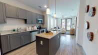 Located at 1001 Linger Longer Dr in Summerville, SC, this single-floor residence offers a thoughtfully designed layout with modern finishes throughout. The kitchen is a standout feature, outfitted with gray shaker-style cabinetry, granite countertops, stainless steel appliances including a refrigerator, electric range, and built-in microwave, and a central island with pendant lighting overhead. Light wood-look flooring flows seamlessly into the combined living and dining area, where an abundance of natural light pours in through multiple large windows dressed with sheer drapes and wood blinds. A ceiling fan, sliding glass door to the exterior, and open sightlines give the living space an airy, comfortable feel. The bedroom is carpeted and well-lit by a large window, complete with a ceiling fan and direct access to a full en-suite bathroom featuring gray cabinetry, a marble-look vanity top, and a tub-shower combination. A second full bathroom mirrors the same refined aesthetic with a single-sink vanity and tub-shower unit. Neutral tones, recessed lighting, and consistent design details create a cohesive and inviting atmosphere throughout the entire home.