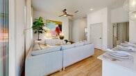 Located in Surprise, AZ, this thoughtfully designed single-story 2-bedroom, 3-bathroom home offers a clean, modern aesthetic with warm, light-filled interiors throughout. The open-concept kitchen is a standout feature, boasting crisp white shaker cabinetry with matte black hardware, light-toned lower cabinets, quartz countertops, and a full suite of stainless steel appliances including a range, over-the-range microwave, dishwasher, and French door refrigerator. Light wood-look flooring runs throughout the main areas, enhancing the bright, airy feel. The living room offers comfortable scale, with natural light streaming through sliding glass doors and windows, complemented by a ceiling fan and recessed lighting. The primary bedroom is a serene retreat with multiple windows and plush carpeting, while the second bedroom provides flexible space suitable as a home office or guest room. Three well-appointed bathrooms include clean white finishes and wood-tone flooring. A dedicated laundry room houses a full-size washer and dryer with overhead cabinetry for added storage. Two closets provide ample organization throughout. The home's consistent use of neutral tones, modern fixtures, and natural light creates a cohesive, inviting atmosphere ideal for comfortable everyday living.