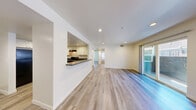 Located at 1500 Karen Ave in Las Vegas, NV, this single-floor residence offers three bedrooms and two bathrooms across a well-organized layout. The open-concept living and kitchen area serves as the heart of the home, featuring light wood-look flooring and recessed lighting throughout. The kitchen is equipped with white shaker-style cabinetry, dark countertops, black appliances including a range and dishwasher, and a pass-through window that connects seamlessly to the living space. The living area extends to a sliding glass door that opens to an outdoor area, allowing natural light to flow in. Each of the three bedrooms is finished with plush carpet and features windows that bring in additional natural light. The primary bedroom is generously sized and includes dedicated closet space. Two full bathrooms serve the home, both featuring wood-look tile flooring, white cabinetry, and dark countertops. One bathroom includes a tiled shower-tub combo with classic white subway tile. A hallway and entrance area provide practical transitional spaces throughout. The overall aesthetic is clean and modern, with a neutral, light-toned palette that creates a bright and cohesive atmosphere throughout the entire residence.