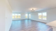 This well-appointed single-story home offers a thoughtfully designed layout across three bedrooms and two bathrooms. The open-concept living and kitchen area serves as the heart of the home, featuring light-toned hardwood-style flooring, crisp white walls, and a modern ring pendant light fixture. Multiple large windows flood the space with natural light while framing scenic outdoor views, creating an airy and expansive atmosphere.

The kitchen is a standout feature, showcasing white shaker-style cabinetry, a large central island with a light countertop, stainless steel appliances including a refrigerator, range, and microwave, and a sleek dark pendant light above the island — combining both style and functionality.

The primary bedroom is generously sized, with hardwood-style flooring, multiple windows offering outdoor views, and access to a dedicated walk-in closet complete with built-in shelving and hanging rods. The additional bedrooms are carpeted in neutral tones and each include windows with outdoor views, providing comfortable and versatile spaces. The bathrooms feature clean, white finishes with a full tub-shower combination. Throughout the home, the consistent use of neutral tones, modern fixtures, and quality materials creates a cohesive, move-in-ready living environment.