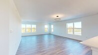 This well-appointed single-story home offers a thoughtfully designed layout across three bedrooms and two bathrooms. The open-concept living and kitchen area serves as the heart of the home, featuring light-toned hardwood-style flooring, crisp white walls, and a modern ring pendant light fixture. Multiple large windows flood the space with natural light while framing scenic outdoor views, creating an airy and expansive atmosphere.

The kitchen is a standout feature, showcasing white shaker-style cabinetry, a large central island with a light countertop, stainless steel appliances including a refrigerator, range, and microwave, and a sleek dark pendant light above the island — combining both style and functionality.

The primary bedroom is generously sized, with hardwood-style flooring, multiple windows offering outdoor views, and access to a dedicated walk-in closet complete with built-in shelving and hanging rods. The additional bedrooms are carpeted in neutral tones and each include windows with outdoor views, providing comfortable and versatile spaces. The bathrooms feature clean, white finishes with a full tub-shower combination. Throughout the home, the consistent use of neutral tones, modern fixtures, and quality materials creates a cohesive, move-in-ready living environment.