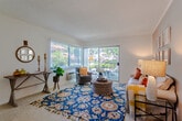 Located at 16350 S Harbor Blvd in Santa Ana, California, this single-floor residence offers a well-organized and inviting layout designed for comfortable everyday living. The living room serves as the heart of the home, featuring neutral wall tones, textured ceilings, and large sliding glass doors that flood the space with natural light and provide direct access to a private outdoor patio with lush greenery views. The open flow leads seamlessly into the dining area, which features wood-look flooring, a ceiling fan with lighting, and a window that brings in additional natural light — creating a warm, casual atmosphere ideal for meals and gatherings. Adjacent to the dining space, the kitchen is efficiently laid out with white cabinetry, granite-style countertops, wood-look flooring, and full appliances including a range, over-the-range microwave, and refrigerator. The bedroom is a serene retreat with plush carpet, neutral accent walls, and a window that allows soft, natural light to filter in. The bathroom is clean and functional, featuring a combination shower and tub, a vanity with stone-style countertops, and wood-look flooring. Throughout the home, a cohesive design palette of warm neutrals creates a welcoming and move-in-ready atmosphere.