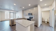 This well-appointed 2-bedroom, 3-bathroom residence in Lakewood, Colorado offers a thoughtfully designed single-floor layout with modern finishes throughout. The open-concept kitchen serves as the heart of the home, featuring a granite-topped center island, light wood-grain cabinetry, a subway tile backsplash, and a full suite of stainless steel appliances including a range, microwave, and dishwasher. Recessed lighting and wood-style flooring extend throughout the main living areas, creating a clean and cohesive aesthetic. A hallway connects the living spaces to the private quarters and also houses a convenient stacked in-unit washer and dryer. The bedrooms offer plush carpeting and natural light through large windows with blinds, providing a comfortable retreat. The primary bedroom includes access to a dedicated bathroom with a granite vanity, modern cabinetry, and a glass-enclosed walk-in shower with white tile surround. A spacious walk-in closet with wire shelving provides ample storage. The additional bathrooms continue the same refined design language. Neutral tones and contemporary hardware selections are consistent throughout, giving the space a cohesive, move-in-ready feel ideal for modern living.