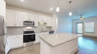 Located in St. Augustine, FL, this single-story, 3-bedroom, 2-bathroom home offers a thoughtfully designed open-concept layout. The kitchen is a standout feature, showcasing white shaker cabinetry, granite countertops, a classic subway tile backsplash, and a full suite of stainless steel appliances including a refrigerator, range, and microwave. A central island with pendant lighting above provides additional prep space and connects seamlessly to the living area, which features wood-look flooring and a ceiling fan. The spacious primary bedroom includes plush carpeting, a ceiling fan, and natural light from a large window. The additional bedrooms are similarly appointed with carpet and ceiling fans, offering comfortable, versatile spaces. Both bathrooms are finished with granite-topped vanities and wood-look flooring; the primary bath includes a glass-enclosed walk-in shower. A dedicated laundry room houses a full-size washer and dryer. Three closets provide ample storage throughout. The home's clean, neutral palette and modern finishes create a bright, cohesive ambiance throughout every room.