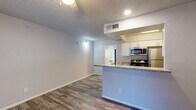 This single-story residence offers a thoughtfully designed open-concept layout that seamlessly connects the living and kitchen areas. Wood-look plank flooring runs throughout the space, providing a warm and cohesive aesthetic, while textured ceilings add a classic touch to each room.

The kitchen is a standout feature, outfitted with crisp white shaker-style cabinetry, granite countertops, and a full suite of stainless steel appliances including a refrigerator, electric range, built-in microwave, and dishwasher. A peninsula counter extends into the living area, creating a natural divide and an ideal spot for casual dining or entertaining. Recessed lighting and pendant fixtures keep the space well-lit.

The living area is open and airy, benefiting from natural light and a neutral gray color palette that complements the flooring. The bedroom is generously proportioned, featuring a ceiling fan, a window with blinds that allows ample natural light, and direct access to a private door. The bathroom continues the refined finishes seen throughout, with a granite-topped vanity, white cabinetry, a large mirror, and updated lighting fixtures. The consistent use of granite and white cabinetry across the kitchen and bathroom creates a polished, unified look throughout the entire residence.
