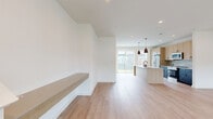 Located in Frisco, TX, this contemporary two-story home offers three bedrooms and three bathrooms with a clean, modern aesthetic carried throughout. The main floor hosts an open-concept kitchen and living area finished with light hardwood-style flooring and recessed lighting. The kitchen is a standout, featuring a large central island with a matte black faucet, light wood cabinetry, dark lower cabinets, a subtle tile backsplash, quartz countertops, stainless steel appliances, and pendant lighting. A sliding glass door floods the space with natural light and provides outdoor access. A built-in floating shelf and staircase accent the living area, adding functional character. A convenient half bath on the main floor includes a wood-tone vanity and black fixtures. Upstairs, the spacious primary bedroom boasts a tray ceiling, ceiling fan, wide windows with neighborhood views, and light hardwood floors. Its en-suite bathroom features a dual-sink vanity, wood cabinetry, black hardware, and a walk-in tiled shower. Two additional carpeted bedrooms include ceiling fans and windows. A well-organized walk-in closet with wire shelving serves the primary suite. The attached two-car garage completes this well-appointed home.
