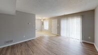 Located at 17 Providence Dr in Smyrna, Delaware, this two-story residence offers a practical and comfortable layout across two well-defined levels. The main floor features a open living and dining area finished with durable wood-style flooring in warm gray tones, complemented by neutral-painted walls and textured ceilings throughout. A sliding glass door with vertical blinds allows natural light to fill the living space, while a ceiling fan adds comfort to the adjoining area near the front entry. The kitchen is efficiently laid out with cream-toned raised-panel cabinetry extending to the ceiling, tile backsplash, a double-basin sink, and white appliances including a range, built-in microwave, and dishwasher. A breakfast bar provides a convenient pass-through connection to the living area. A staircase with white railings leads to the upper level, where carpeted bedrooms offer a quiet retreat. The bedrooms feature neutral gray walls, textured ceilings, and natural light from windows with blinds. One bedroom includes mirrored sliding closet doors, adding a sense of depth and storage. The bathroom is clean and straightforward, finished with white square tile and standard fixtures. Overall, the home presents a tidy, move-in-ready environment with a cohesive neutral palette throughout.