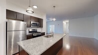 Located at 750 Summer St in Stamford, CT, this well-designed two-bedroom, two-bathroom residence offers a thoughtful single-floor layout that balances open-concept living with private retreats. The kitchen serves as a central highlight, featuring a large granite-topped island with an undermount sink, dark espresso cabinetry, stainless steel appliances including a gas range, microwave, and refrigerator, and stylish pendant lighting. The kitchen flows seamlessly into the dining area and a spacious living room finished with rich hardwood floors and track lighting, creating a cohesive and inviting common area. A pantry closet adjacent to the kitchen provides convenient additional storage. Both bedrooms are carpeted for comfort and receive natural light through large windows fitted with blinds, offering views of the surrounding neighborhood. The primary bedroom is generously sized, providing ample room for furnishings. Each bathroom is finished in a contemporary style with tile flooring, a floating dark-wood vanity, and a soaking tub. A hallway connects the private areas of the home, contributing to an efficient and functional floor plan. The clean, neutral palette throughout creates a bright and versatile living environment well-suited for a variety of lifestyles.