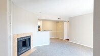 Located at 8380 El Mundo St in Houston, TX, this single-floor residence offers 2 bedrooms and 2 bathrooms thoughtfully arranged for comfortable everyday living. The welcoming entrance opens into a spacious living room anchored by a standout tile-surround fireplace with built-in shelving, adding both warmth and character to the space. Soft carpeting flows throughout the living and bedroom areas, while natural light filters in through slatted blinds. The open-concept layout connects the living room to the kitchen via a half-wall pass-through, creating a cohesive and social atmosphere. The kitchen is well-appointed with white cabinetry, a travertine tile backsplash, dark granite countertops, stainless steel appliances including a dishwasher and microwave, and rich hardwood-style flooring. An in-unit washer and dryer area is conveniently tucked within the kitchen space. Both bedrooms are carpeted and feature ceiling fans with light fixtures and windows that bring in natural light. The bathrooms include a tub-shower combination with white cabinetry for overhead storage and hardwood-style flooring. Each bedroom benefits from dedicated closet space, completing a practical and well-organized layout throughout this Houston residence.