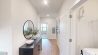 Located in Huntsville, AL, this thoughtfully designed 2-bedroom, 2-bathroom single-story residence combines modern aesthetics with functional living. The interior is defined by a clean, neutral palette featuring crisp white walls, light wood-style flooring throughout the main areas, and an abundance of natural light from well-placed windows fitted with white blinds.

The welcoming hallway sets the tone with recessed lighting and a sense of openness that carries through the entire floor plan. The living area features a glass-paneled exterior door that fills the space with natural light and provides direct outdoor access, offering views of the surrounding community.

Both bedrooms are generously proportioned, carpeted for comfort, and equipped with ceiling fans. The primary bedroom includes an ensuite bathroom and a dedicated closet, while the second bedroom is similarly well-appointed with its own closet. The primary bath features a glass-enclosed walk-in shower, while the secondary bath offers a tub-shower combination — both finished with granite-topped vanities, gray cabinetry, and tile flooring.

The layout is completed by a central hallway that connects all spaces efficiently, providing a cohesive and comfortable flow throughout this well-appointed Huntsville residence.