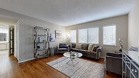 This thoughtfully designed single-story residence in Averdine offers a complete and functional layout across one floor, encompassing a living room, dining room, kitchen, bedroom, bathroom, entrance, and hallway. The living room is a standout space, featuring warm hardwood flooring, a textured ceiling, and a generous bank of windows dressed with white blinds that invite ample natural light. A distinctive arched entryway connects the hallway to the living area, adding an elegant architectural detail that enhances the overall character of the home. The kitchen is well-equipped with cream-toned cabinetry, tile flooring, a double sink, and a full suite of white appliances, including a dishwasher and range. The bedroom is a comfortable, well-proportioned retreat with continued hardwood flooring, a window for natural light, and a louvered closet door providing convenient storage access. The bathroom features tile flooring, a vanity with a marble-style countertop, a large mirror with overhead lighting, and an open shelving unit for additional storage. Neutral, warm tones throughout the home create a cohesive and inviting ambiance, making this residence a well-balanced and practical living space.