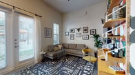 This single-floor space combines contemporary design with functional living across its key areas. The living room serves as a focal point, featuring a sectional sofa atop a bold geometric-patterned rug, with tall ceilings and large windows dressed in sheer white curtains that allow abundant natural light. A curated gallery wall displaying framed photographs alongside a decorative bull skull mount adds personality to the neutral-toned walls, while an adjacent wood desk and open shelving provide a practical workspace.

The kitchen is outfitted with floor-to-ceiling dark espresso cabinetry, granite countertops, a white subway tile backsplash, and a full suite of stainless steel appliances including a range, microwave, dishwasher, and refrigerator. Polished concrete flooring extends through the kitchen and bathroom, lending an industrial yet refined aesthetic. A glass door with sheer drapery brightens the kitchen with outdoor views.

The bedroom is a calm retreat finished with soft carpet, neutral gray walls, and a low-profile bed framed by textured white sculptural wall panels. A walk-in closet provides ample storage. The bathroom features a granite-topped dark vanity, a tub-shower combination, and polished concrete floors, maintaining the cohesive modern style found throughout the space.
