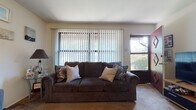 This single-floor residence offers a well-organized layout with distinct living, dining, kitchen, and bedroom areas. The living room serves as the heart of the home, featuring warm carpeted flooring, a ceiling fan, and large windows fitted with vertical blinds that allow for natural light while maintaining privacy. The space is versatile, accommodating both a relaxed seating arrangement and an entertainment setup with dedicated media storage.

The kitchen is a functional galley-style space finished with wood-look flooring, dark wood cabinetry, and a window that lets in natural light. It includes a wall oven and a refrigerator, providing practical cooking amenities.

The bedrooms are carpeted and offer comfortable proportions with ample natural light from individual windows fitted with blinds. One bedroom features a cozy, personalized atmosphere with bold accent curtains, while another presents a more open, versatile layout suitable for various configurations.

Throughout the residence, the neutral wall palette and carpeted floors in the main living areas create a cohesive, livable ambiance. The open sightlines between the living room and kitchen area lend a connected feel to the common spaces, making the overall layout feel welcoming and easy to navigate.
