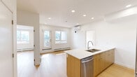 Located at 110 Lucas St NW in Calgary, Alberta, this well-designed 2-bedroom, 2-bathroom unit offers a thoughtfully laid-out single-floor plan. The contemporary kitchen serves as a focal point, featuring a large island with a white quartz countertop, dual-tone cabinetry combining white upper cabinets with warm wood-finish lower cabinets, stainless steel appliances including a refrigerator and range, and recessed lighting throughout. Light-toned hardwood flooring runs consistently across the living areas and bedrooms, lending the space a clean, cohesive aesthetic. Both bedrooms are bright and airy, each benefiting from sliding windows that invite natural light and offer views of the surrounding residential neighbourhood. Baseboard heating is present in the bedrooms for year-round comfort. The two bathrooms are finished in a neutral palette, each equipped with a full soaker tub and shower combination with tiled surround detailing. A dedicated in-unit laundry room houses a stacked Samsung washer and dryer set, adding practical convenience. The unit also includes a private balcony with metal railing, overlooking Lucas Street and the developing community beyond. A connecting hallway ties all rooms together efficiently, completing this functional and modern living space.
