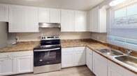 Located at 5204 Lancelot Ln NW in Roanoke, Virginia, this two-floor home offers a well-designed layout with a blend of functional updates and comfortable living spaces throughout. The main living area features smooth hardwood-style flooring and a generous sliding glass door that fills the room with natural light while offering a pleasant view of the surrounding greenery outside.

The kitchen is a standout feature, equipped with crisp white shaker-style cabinetry, granite-style countertops, a tiled backsplash, and stainless steel appliances including a Whirlpool electric range with a range hood above. A stainless steel sink completes the workspace, making this kitchen both practical and visually appealing.

The bedrooms are carpeted and well-lit, each featuring windows that bring in natural light. The rooms offer ample space and include closet access, providing comfortable and flexible living areas.

The bathrooms are finished with classic square tile wainscoting. One bathroom features a tub-shower combination with white tile surround and a granite-style vanity countertop, while a second bathroom includes a glass-door walk-in shower stall with matching tile work. Additional living areas with hardwood-style flooring round out the lower level. The home's neutral color palette and clean finishes create a bright, move-in-ready atmosphere throughout.