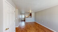 Located at 7000 North Buckingham Square in Columbia, Missouri, this two-bedroom, one-bathroom residence offers a straightforward and functional single-floor layout designed for comfortable everyday living. The living room serves as the welcoming centerpiece of the home, featuring warm hardwood-style flooring, neutral gray walls, and a window that allows natural light to brighten the space. The galley-style kitchen is efficiently arranged with light wood cabinetry providing ample storage, laminate countertops, a coil-top electric range, a refrigerator, and a dishwasher — all set atop matching hardwood-style flooring that flows seamlessly from the living area. Both bedrooms are carpeted in a neutral tone, creating a soft and comfortable feel. The primary bedroom offers a generous footprint with a dedicated closet, while the second bedroom features its own window, bringing in natural light. A full bathroom serves the unit, complete with a tub-shower combination, tile flooring, and a vanity. Textured ceilings are consistent throughout the home, and clean white trim and panel-style doors add a cohesive finishing touch. The layout is practical and well-organized, making efficient use of the available space throughout.