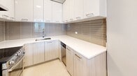 Located at 2150 Boulevard De Maisonneuve Ouest in Montréal, this 1-bedroom, 1-bathroom unit offers a clean, modern aesthetic throughout its thoughtfully arranged single floor. Light-toned laminate flooring runs continuously through the space, complementing the soft neutral palette of the walls and ceilings and creating a bright, cohesive feel.

The open-concept living, dining, and kitchen area forms the heart of the unit. The kitchen is well-appointed with an L-shaped layout featuring light wood-grain lower cabinetry, high-gloss white upper cabinets, white countertops, a stainless steel sink, a dishwasher, and a stylish metallic tile backsplash that adds texture and visual interest. A hallway with track lighting leads toward the living area, which benefits from large windows offering urban views of the surrounding Montréal cityscape and ample natural light.

The bedroom is a comfortable, well-proportioned room with a broad window overlooking the city, a baseboard heating unit, and a dedicated closet with built-in shelving and a hanging rod. A built-in wardrobe unit adds additional storage. The bathroom completes the layout. Overall, the unit presents a clean, minimalist character with modern finishes throughout.