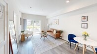 Located at 10555 Bloomfield St in the Los Feliz neighborhood of Los Angeles, this single-floor unit offers a thoughtfully designed layout with contemporary finishes throughout. Light-toned hardwood flooring runs continuously through the space, creating a cohesive and airy atmosphere.

The living area is generously proportioned, bathed in natural light from large sliding glass doors that open directly onto a private outdoor patio. The patio provides a comfortable al fresco seating area surrounded by greenery, making it an ideal extension of the interior living space. Recessed lighting and clean white walls keep the interior bright and versatile.

The bedroom is a tranquil retreat, featuring a large window fitted with horizontal blinds that allow for adjustable natural light. The room comfortably accommodates a queen-sized bed and offers a calm, neutral aesthetic with warm wood flooring underfoot.

The kitchen is efficiently integrated into the open-concept floor plan, maintaining the unit's streamlined design. The bathroom is finished with classic white subway tile surrounding the full soaking tub and shower combination, complemented by a modern vanity with a dark countertop, undermount sink, and white cabinetry. Together, these spaces deliver a clean, modern living experience in a well-connected Los Angeles location.