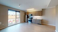 Located at 1280 SE Nehalem St in Portland, Oregon, this modern single-floor unit offers a thoughtfully designed layout with contemporary finishes throughout. The open-concept living and kitchen area forms the heart of the space, featuring light wood-tone luxury vinyl plank flooring that extends seamlessly across all rooms, creating a cohesive and clean aesthetic.

The kitchen is well-appointed with a full suite of stainless steel appliances, including a gas range, over-the-range microwave, refrigerator, and dishwasher. Warm wood-toned upper and lower cabinetry provides ample storage, complemented by light countertops and a white tile backsplash. A large window in the kitchen area invites abundant natural light and offers views of the surrounding neighborhood.

The living area flows naturally from the kitchen, providing generous open space with access to additional rooms. The bedroom features an oversized window with roller shade, flooding the room with natural light and framing views of the tree-lined Portland streetscape.

The bathroom is finished with neutral tones, featuring a single-sink vanity with wood-grain cabinetry, a full tub-shower combination, and light flooring that mirrors the rest of the unit. Throughout the space, the modern, minimalist design and natural light create a bright, functional, and welcoming environment.