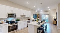 Located at University Executive Park in Charlotte, NC, this one-bedroom, one-bathroom residence offers a thoughtfully designed open-concept layout with modern finishes throughout. Light-toned hardwood flooring flows seamlessly across the entire space, enhancing the bright and airy atmosphere created by recessed lighting and large windows.

The kitchen is a standout feature, showcasing crisp white shaker cabinets, a neutral tile backsplash, stainless steel appliances — including a refrigerator, range, microwave, and dishwasher — and a generous island with bar seating illuminated by pendant lighting. The kitchen opens directly into the living area, making the space ideal for entertaining. Sliding glass doors in the living room lead to a private balcony, filling the room with natural light and outdoor views.

The bedroom is a comfortable retreat with a window allowing natural light, and direct access to a dedicated closet. The bathroom features a dual-sink vanity with white cabinetry, a large mirror, and hardwood-style flooring, maintaining the clean, contemporary aesthetic found throughout the home. The overall ambiance is modern, cohesive, and move-in ready.