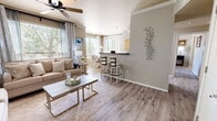 Located at 6200 Montano Plaza Dr NW in Albuquerque, New Mexico, this well-appointed three-bedroom, three-bathroom single-floor residence offers a thoughtfully designed open-concept layout. The living and dining area is highlighted by light wood-look flooring, crown molding, a ceiling fan, and large windows dressed with layered curtains and blinds that invite generous natural light and outdoor views of surrounding greenery. A breakfast bar with a curved granite countertop connects the living space to the kitchen, which features light wood cabinetry, dark appliances, and track lighting overhead. The adjacent dining area benefits from its own large window, creating a bright and airy setting for meals. Each of the three bedrooms offers a comfortable and functional retreat; the primary bedroom includes a walk-in closet and ample space for a workspace, while additional bedrooms are equally well-sized with natural light and hardwood-style flooring. The three bathrooms are finished with granite-style countertops and full mirrors. A dedicated in-unit laundry room with side-by-side washer and dryer and built-in shelving adds everyday convenience. Neutral warm-gray tones throughout create a cohesive, modern ambiance across this efficiently designed home.