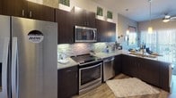 Located at 8275 Walnut Hill Ln in Dallas, Texas, this single-floor residence offers a thoughtfully designed layout with modern finishes and functional living spaces. The kitchen is a standout feature, showcasing rich dark espresso cabinetry that extends to the ceiling, granite countertops, a mosaic tile backsplash with under-cabinet lighting, and a full suite of stainless steel Whirlpool appliances including a French door refrigerator, range, microwave, and dishwasher. Light wood-tone flooring runs throughout, adding warmth and visual continuity across the space. The bedroom is a serene retreat, complete with a ceiling fan, neutral wall tones, and a window fitted with horizontal blinds that allow natural light to filter in softly. A walk-in closet connects directly to the bathroom, offering built-in shelving and double hanging rods for organized storage. Light wood flooring continues into the closet, maintaining a cohesive aesthetic. The overall ambiance of the unit is clean, contemporary, and move-in ready, with a neutral color palette and modern fixtures that create a comfortable and stylish living environment in the heart of Dallas.