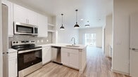 Located at 624 North Lancaster Avenue in Dallas, TX, this thoughtfully designed one-bedroom, one-bathroom unit offers a clean, modern aesthetic throughout. Light-toned luxury vinyl plank flooring flows seamlessly across the entire space, enhancing the bright and airy atmosphere created by the white walls and recessed lighting.

The open-concept kitchen and living area serves as the heart of the unit. The kitchen is outfitted with crisp white shaker cabinetry, a tiled backsplash, and a full suite of stainless steel appliances including a refrigerator, range, microwave, and dishwasher. A peninsula island with a single-basin sink and pendant lighting above adds both function and style. A built-in desk with overhead cabinets provides a dedicated workspace neatly integrated into the layout.

The living area extends naturally from the kitchen toward a sliding glass door that opens to a private balcony with outdoor views. The bedroom is a comfortable retreat featuring two windows that invite natural light, a ceiling fan, a closet, and direct access to the balcony. The bathroom includes a soaking tub and shower combination with floor-to-ceiling tile surround, a white vanity, and wood-look flooring. A dedicated laundry area completes this well-appointed unit.