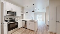 Located at 624 North Lancaster Avenue in Dallas, TX, this thoughtfully designed one-bedroom, one-bathroom unit offers a clean, modern aesthetic throughout. Light-toned luxury vinyl plank flooring flows seamlessly across the entire space, enhancing the bright and airy atmosphere created by the white walls and recessed lighting.

The open-concept kitchen and living area serves as the heart of the unit. The kitchen is outfitted with crisp white shaker cabinetry, a tiled backsplash, and a full suite of stainless steel appliances including a refrigerator, range, microwave, and dishwasher. A peninsula island with a single-basin sink and pendant lighting above adds both function and style. A built-in desk with overhead cabinets provides a dedicated workspace neatly integrated into the layout.

The living area extends naturally from the kitchen toward a sliding glass door that opens to a private balcony with outdoor views. The bedroom is a comfortable retreat featuring two windows that invite natural light, a ceiling fan, a closet, and direct access to the balcony. The bathroom includes a soaking tub and shower combination with floor-to-ceiling tile surround, a white vanity, and wood-look flooring. A dedicated laundry area completes this well-appointed unit.