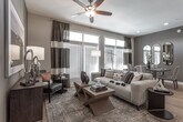 This single-story residence on E Mayo Blvd in Phoenix, Arizona, presents a thoughtfully designed open-concept floor plan with contemporary finishes and a cohesive neutral color palette. The kitchen serves as a central hub of the living area, featuring gray shaker-style cabinetry with glass-front upper cabinets, stainless steel appliances including a gas range, built-in microwave, and French door refrigerator, plus a large island with white quartz countertops, an undermount sink with a high-arc faucet, and seating for multiple guests. Brushed nickel pendant lights illuminate the island, complementing the light hardwood flooring that flows into the open dining and living areas. The living room offers generous natural light through a bank of large windows, with a ceiling fan overhead and ample space for relaxed seating arrangements. Multiple bedrooms provide comfortable retreats, each with plush carpet, ceiling fans, and natural light. The bathrooms are finished with tile flooring, shaker-style vanities with white countertops, and large mirrors. One bathroom features a dual-sink vanity with a separate shower, while another includes a soaking tub and walk-in closet access, adding functional versatility to the overall layout.