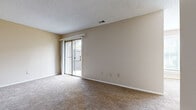 Located at 7929 Sycamore Ave in Kansas City, MO, this single-floor, one-bedroom, one-bathroom unit offers a well-organized layout across a compact yet functional footprint. The living room is carpeted and features a sliding glass door that opens to an outdoor patio area, allowing natural light to fill the space and providing outdoor views. A ceiling fan with a light fixture adds practical comfort to both the living and dining areas, which flow openly into one another. The dining room benefits from a large triple-pane window overlooking a green outdoor setting, further enhancing the sense of light and openness. The galley-style kitchen is efficiently designed with white cabinetry, dark countertops, hardwood-style flooring, a double-basin sink, a dishwasher, and black appliances including a range and refrigerator with overhead ventilation. The bedroom is carpeted and includes a sliding-door closet with a built-in rod and shelving for storage, along with a window that brings in natural light. The bathroom features a full-size soaking tub and shower combination with clean white tile surround and chrome fixtures. Textured ceilings are present throughout, and neutral warm-beige tones unify the interiors.