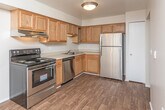 Located at 1901 Chene Ct in Detroit, Michigan, this single-floor unit offers a well-organized layout designed for comfortable everyday living. The kitchen is outfitted with warm-toned oak cabinetry, stainless steel appliances including a range, dishwasher, and refrigerator, along with a built-in sink and ample upper and lower cabinet storage. Light wood-style flooring runs throughout the kitchen and flows seamlessly into the open living and dining areas, creating a cohesive and inviting atmosphere. The living room is generously sized, featuring large floor-to-ceiling vertical blinds that allow abundant natural light to fill the space. A second sizable room, also carpeted, benefits from dual windows that bring in additional natural light. The bedrooms are carpeted for comfort, with one bedroom featuring a walk-in closet equipped with built-in shelving, offering excellent storage capacity. The full bathroom includes a tiled shower-tub combination, a single-sink vanity with oak cabinetry, and a large mirror. Throughout the unit, neutral wall tones and clean finishes contribute to a bright, move-in-ready environment suited for a variety of living arrangements.
